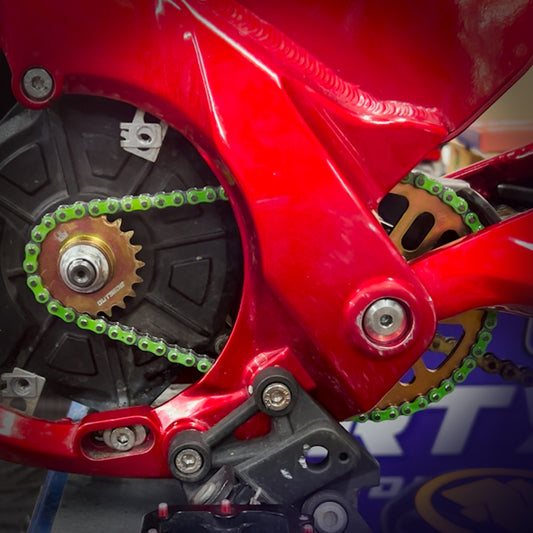 Closeup of green 219 RK chain kit on red Talaria XXX electric motorbike