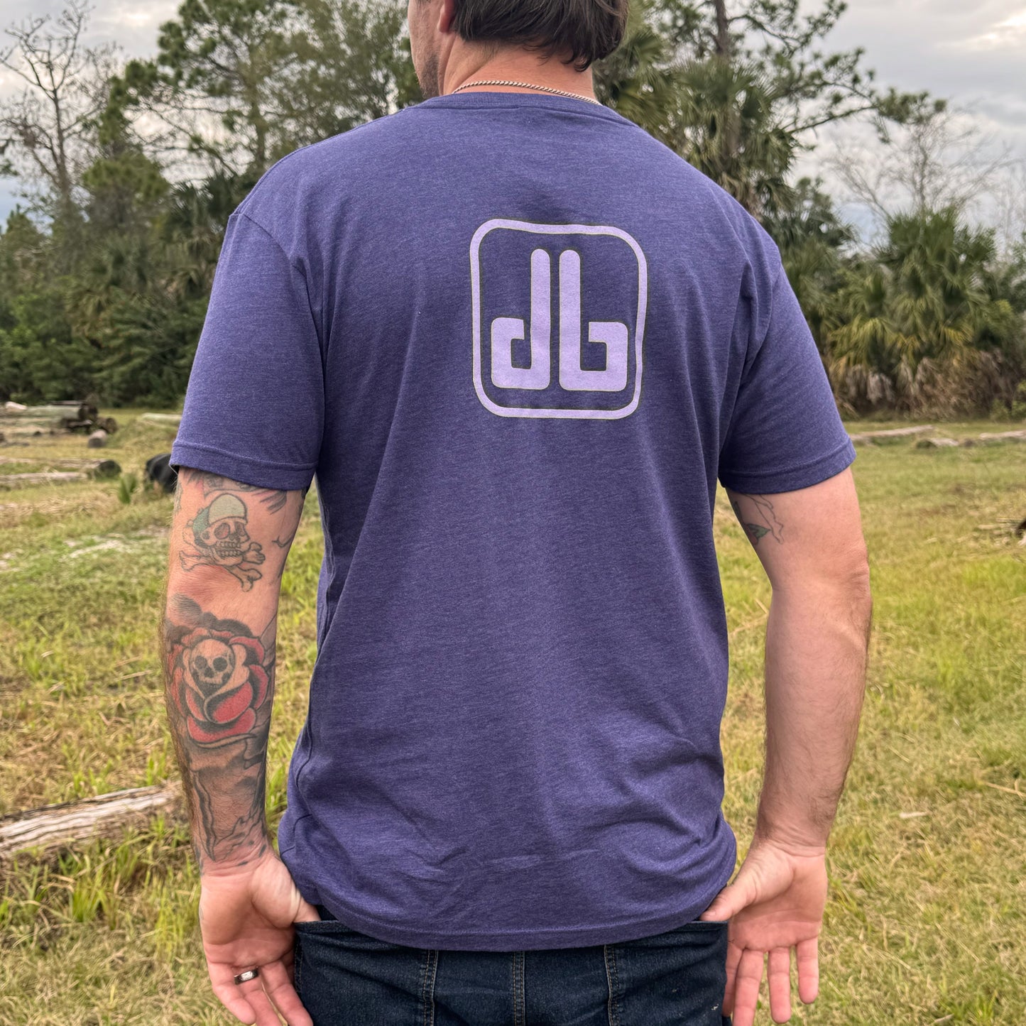 Person wearing a purple t-shirt with a db logo outdoors