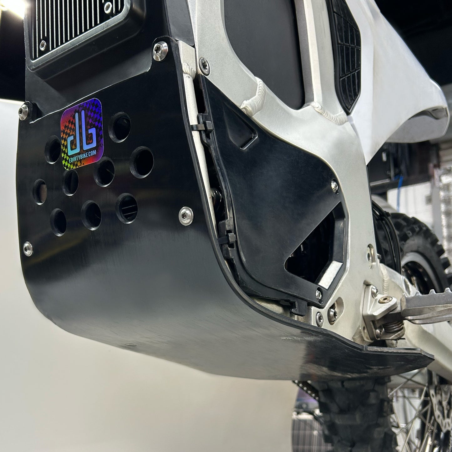 close up of a vented plastic skid plate underneath the frame of an electric motorcycle
