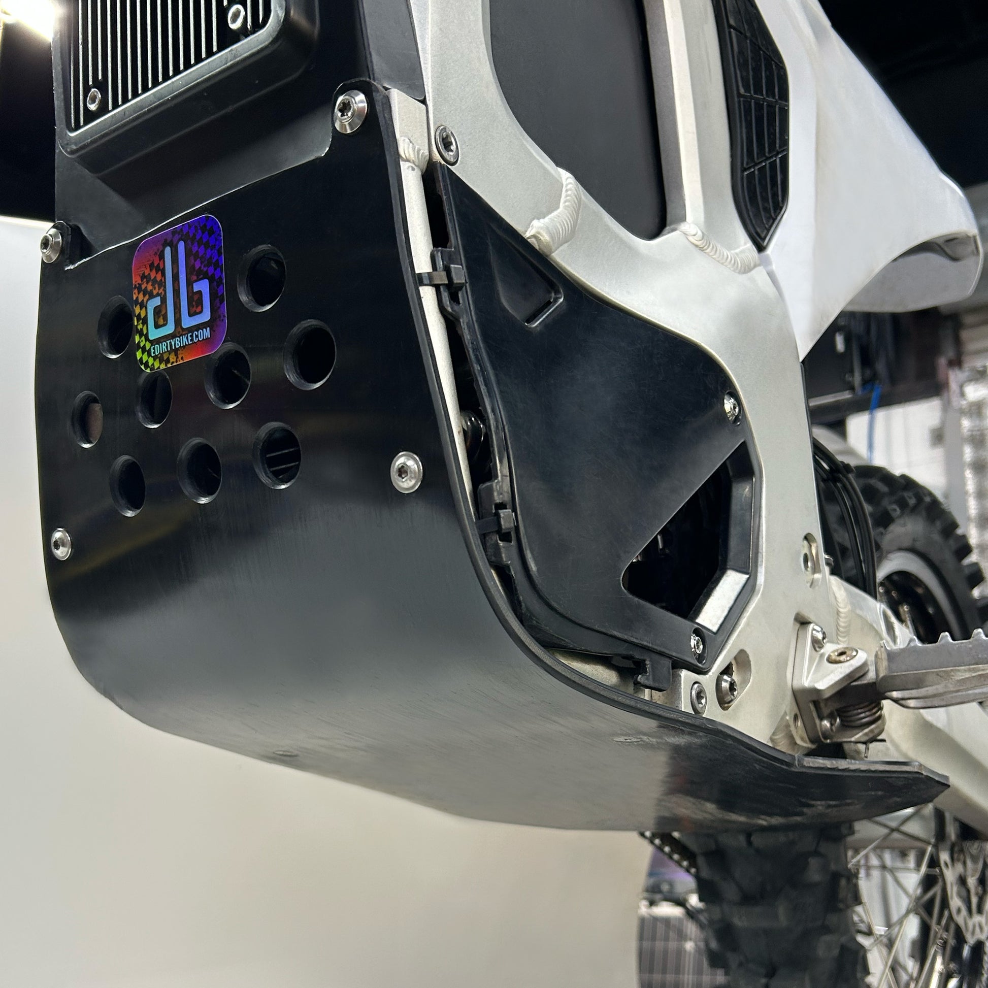 close up of a vented plastic skid plate underneath the frame of an electric motorcycle