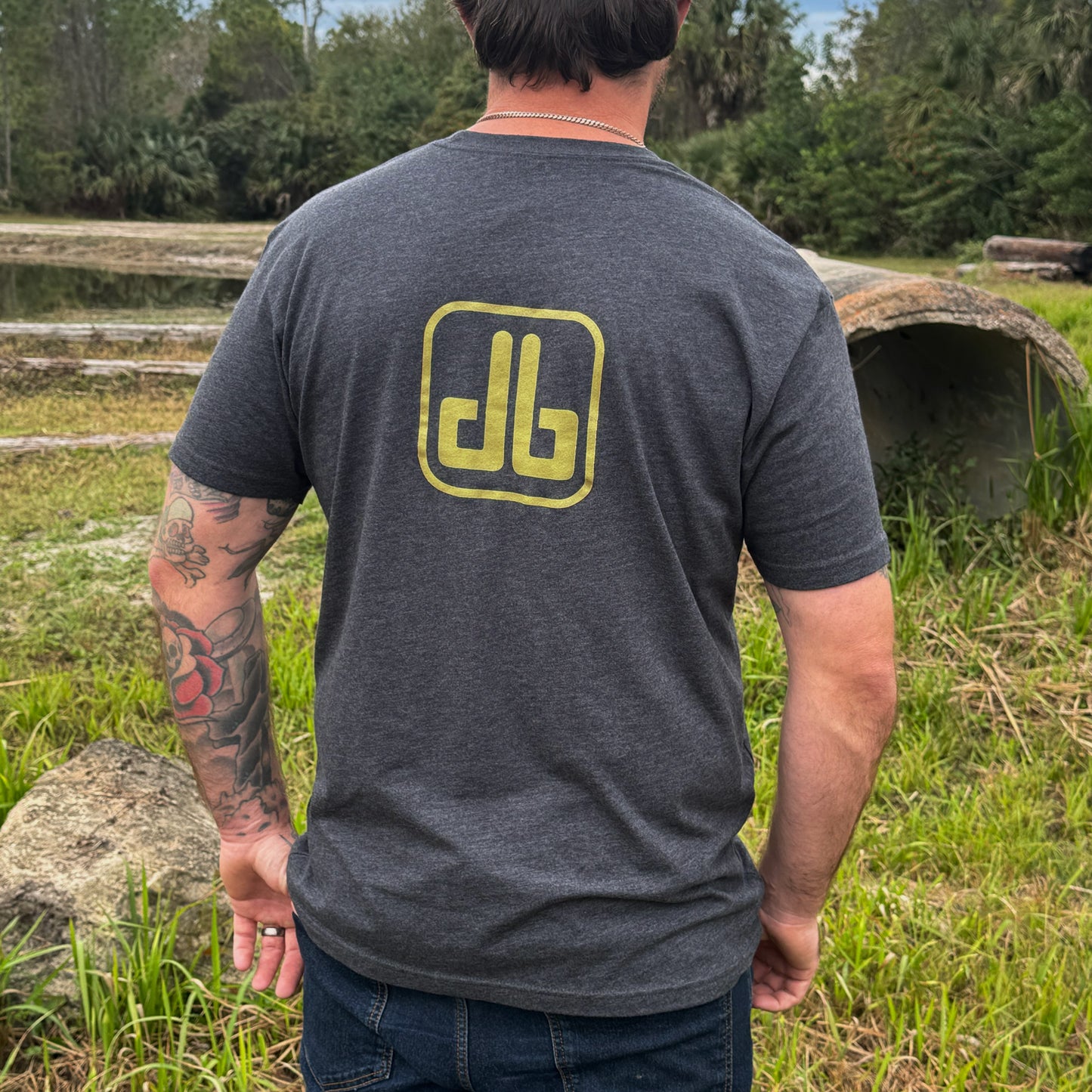 Person wearing a gray t-shirt with a yellow db logo outdoors