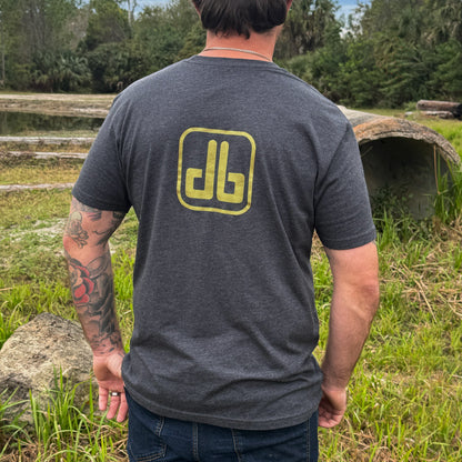 Person wearing a gray t-shirt with a yellow db logo outdoors