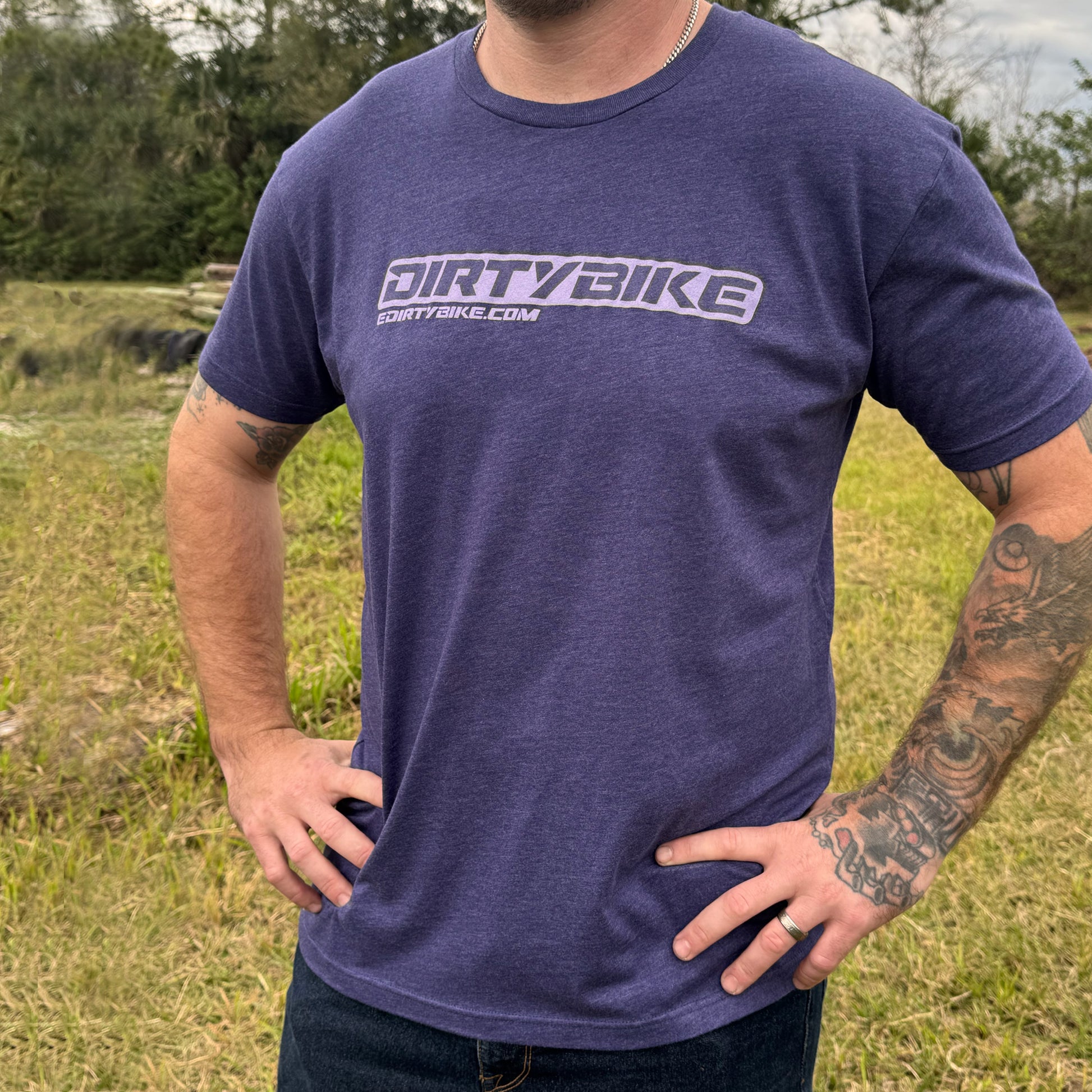 Person wearing a purple 'DIRTYBIKE' t-shirt outdoors.